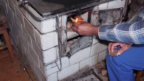 el hombre enciende una madera en una vieja estufa de cocina rústica con un fósforo