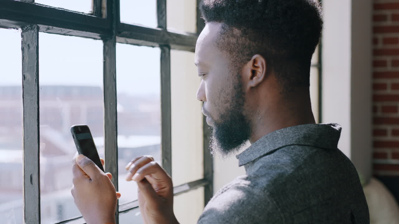Business black man on smartphone at a window