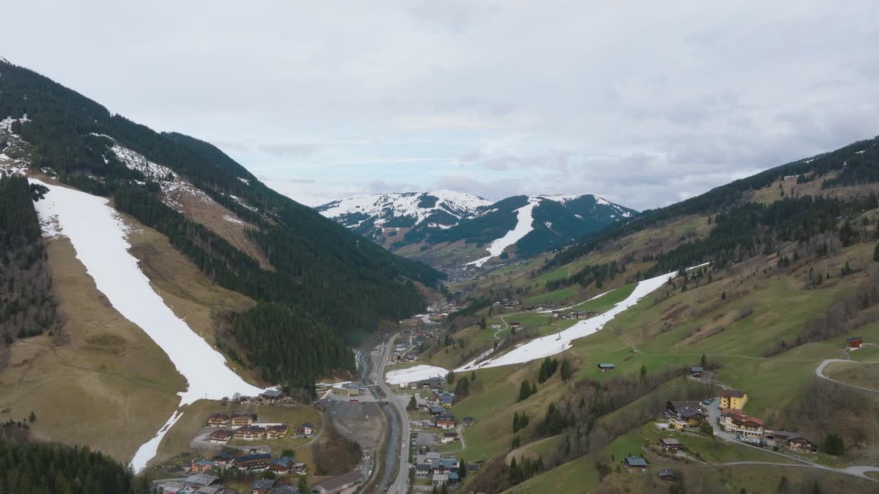 saalbach-hinterglemm, descendiendo hacia una estación de esquí alpina con nieve irregular en primavera, vista aérea