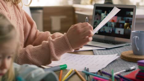 Video-of-young-female-teacher-teaching-remotely-while-daughter-drawing