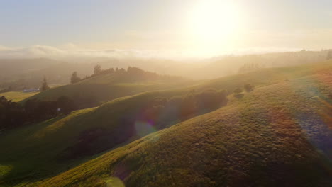 Aerial-cinematic-view-of-hills-with-afternoon-mist-and-golden-hour-sun-rays-in-the-evening