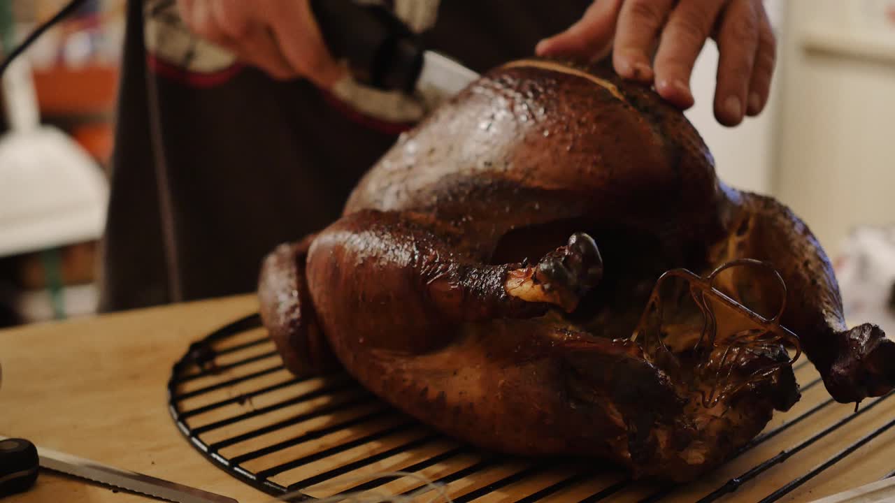 A cooked turkey being carved with an electric knife