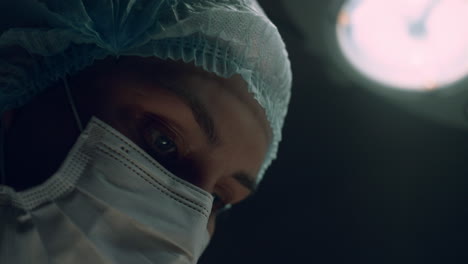 portrait surgeon performing operation in dark hospital intensive care unit room