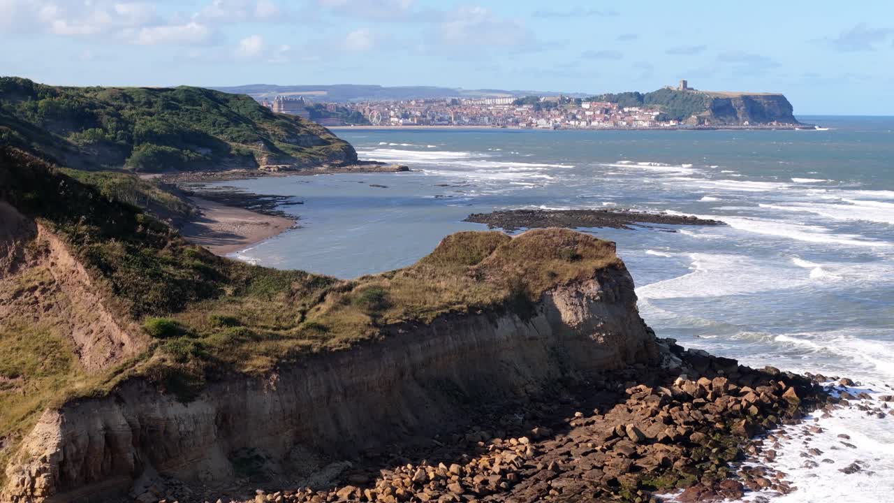 Riprese aeree con drone di Cornelian Bay e Cayton Bay, Scarborough, con cielo blu, oceano e grandi onde.