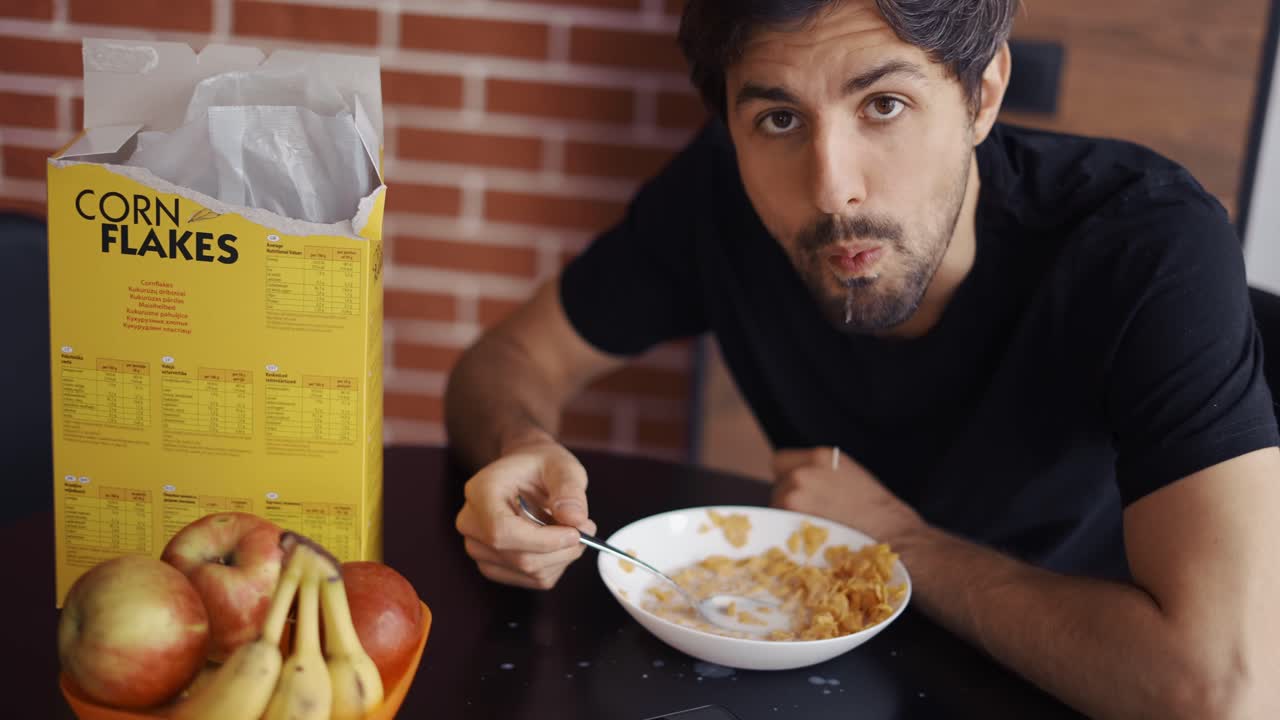 un tipo tomando copos de maíz, posando graciosamente para la cámara, haciendo tonterías