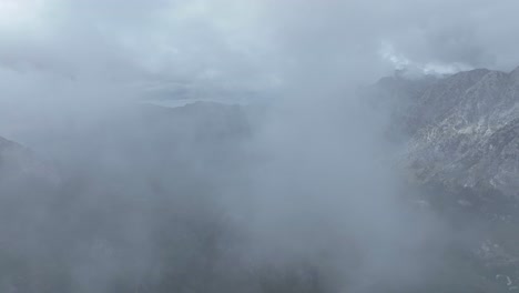 flying through the clouds over the mountain range near theth village in shkoder county, albania. - aerial shot
