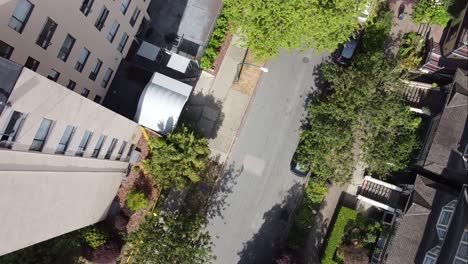 1-2-Twisted-spiral-aerial-birds-eye-view-over-victorian-residential-detached-homes-across-a-10-storey-high-apartment-building-on-a-sunny-summer-day-in-a-tropical-foilage-urban-inner-street-district