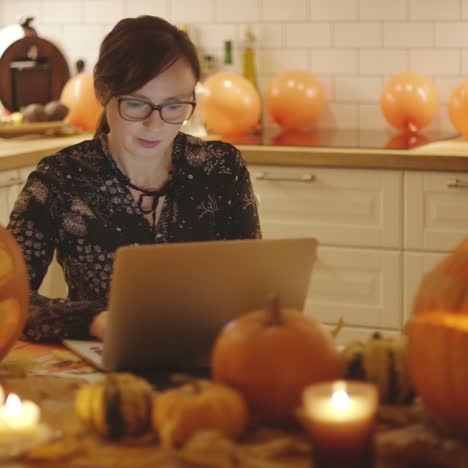 Frau-Mit-Laptop-In-Der-Nähe-Von-Halloween-Dekorationen