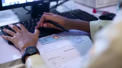 el cajero del trabajador de la salud está ingresando datos del paciente con una tarjeta de identidad en el mostrador de registro del hospital usando una computadora