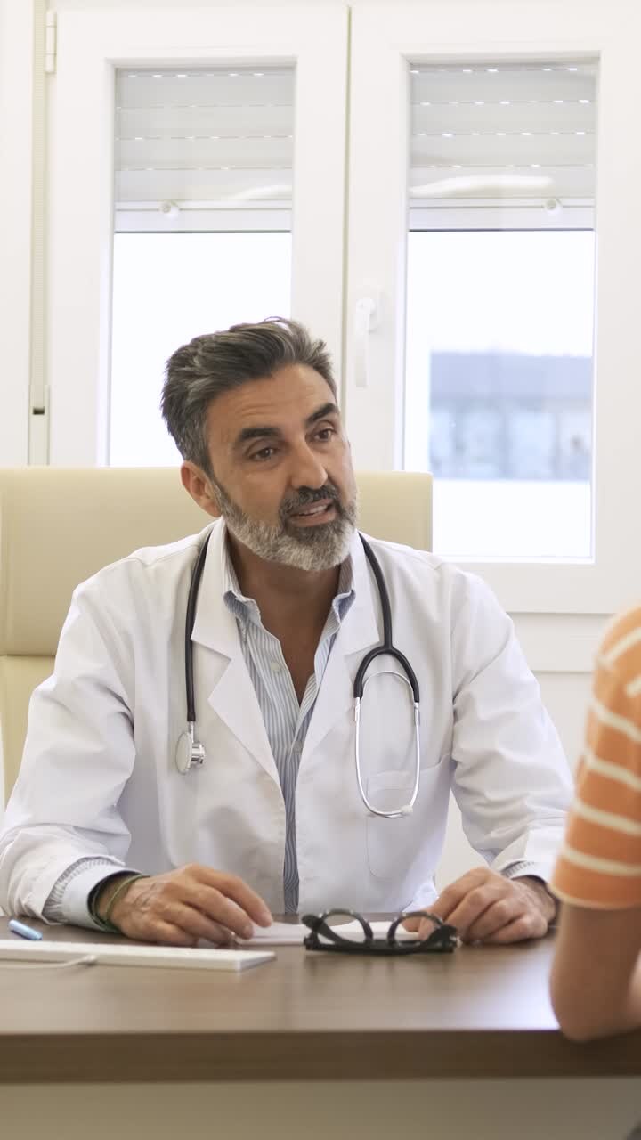 Confident male doctor talking to patient in clinic during daytime