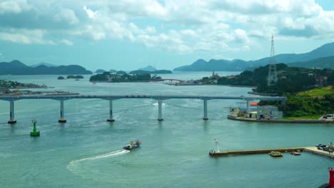 fishing boat sailing across the geoje bridge with traffic in geojedo island, south korea