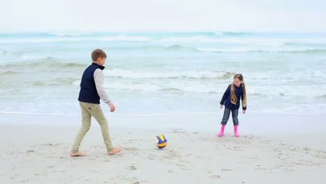 siblings playing football on the beach