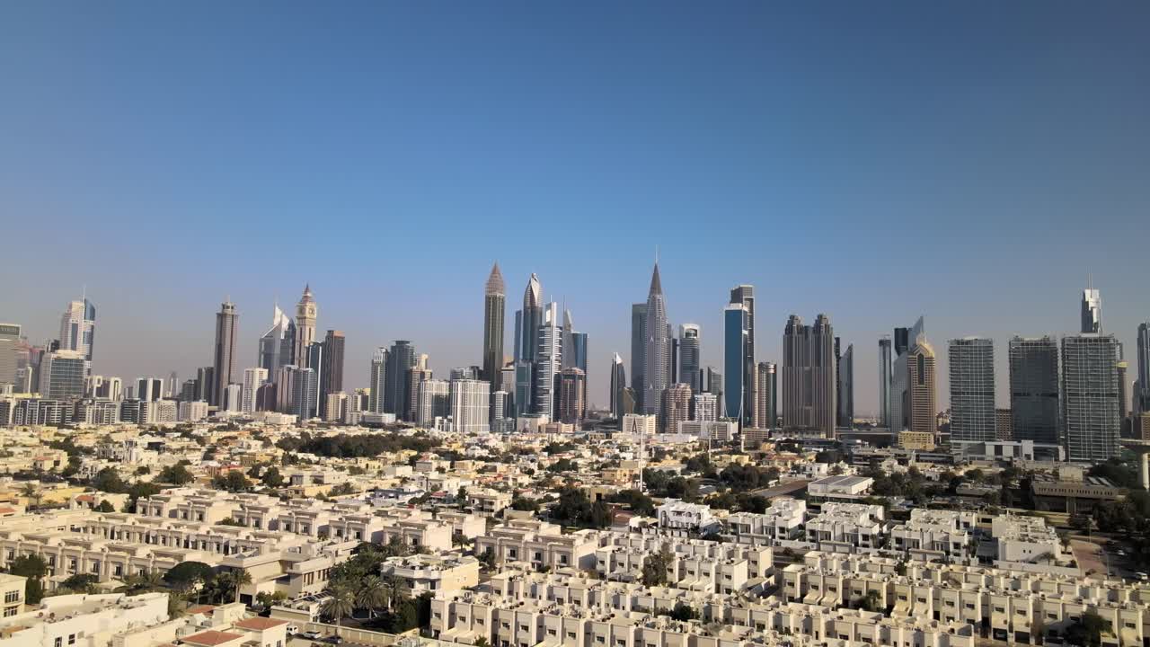 뒤로 찍은 드론은 교외 지역과 두바이의 현대적인 스카이라인을 배경으로 보여줍니다. 푸른 하늘과 함께 아름다운  ⁇ 은 날입니다.