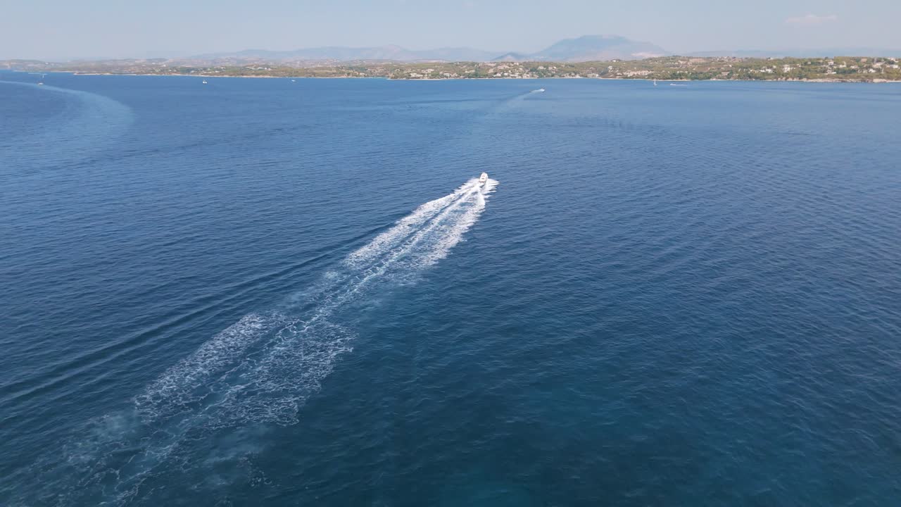 Motoscafo su mare blu che crea una scia bianca, giornata di sole, costa remota.