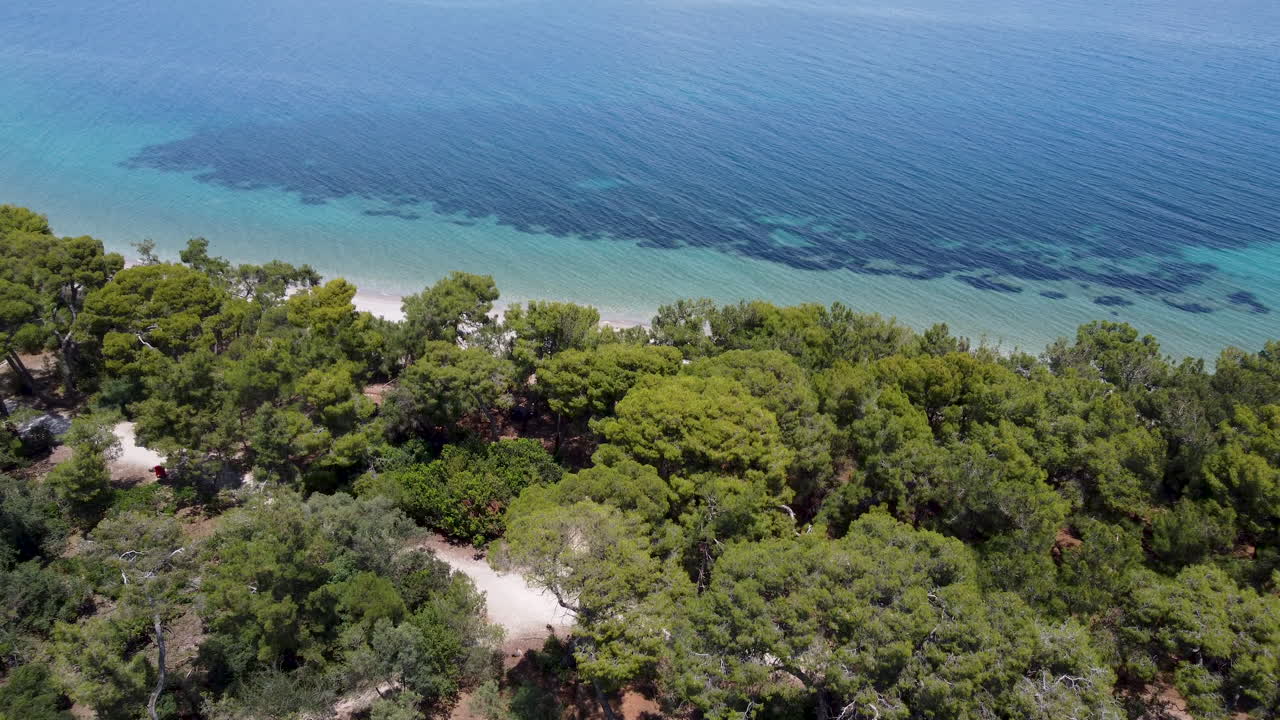 Un drone si tuffa oltre una foresta rivelando la spiaggia in Grecia