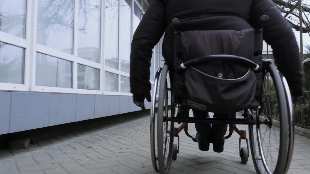 una persona con discapacidad se mueve por la calle en silla de ruedas