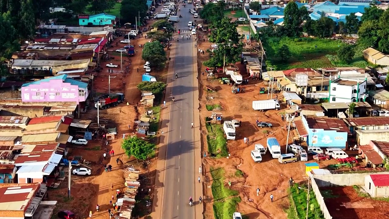 Strade del Kenya, strade rurali, insediamento rurale povero, strada danneggiata con drone che riprende veicoli sulla strada dall'alto
