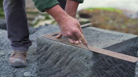 Handheld-shot-of-a-stone-craftsman-marking-a-cancagua-stone-with-a-right-angle,-in-the-city-of-Ancud,-Chiloe-Island