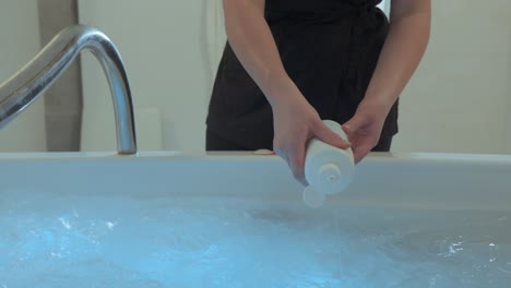 hand-held shot of a employee putting bubble bath into a spa pool