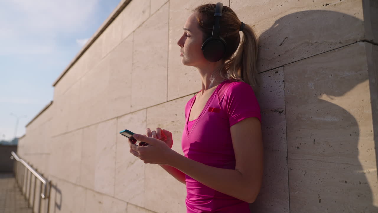 mujer escuchando música y usando el teléfono mientras está al aire libre