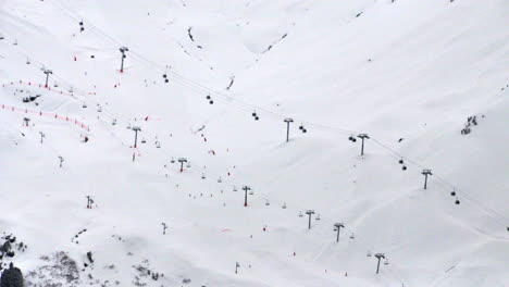 Lapso-De-Tiempo-De-2-Remontes-En-La-Ladera-De-Una-Montaña-Con-Gente-Esquiando-Debajo,-En-La-Estación-De-Meribel-En-Los-Alpes-Franceses-En-Invierno