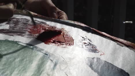 female artist mixes yellow with red paint on her palette outside at sunset with palette knife, camera pans right