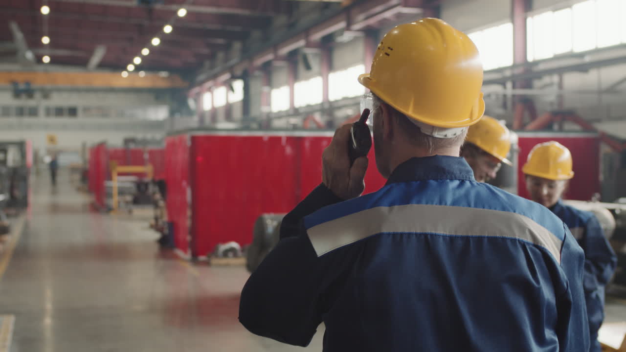 Supervisor Giving Instructions On Walkie-Talkie At Plant Facility