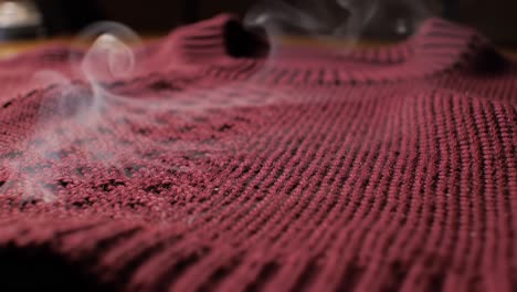 Smoke Rises From a Burned Knitted Sweater During Crafting Session in a Cozy Indoor Setting