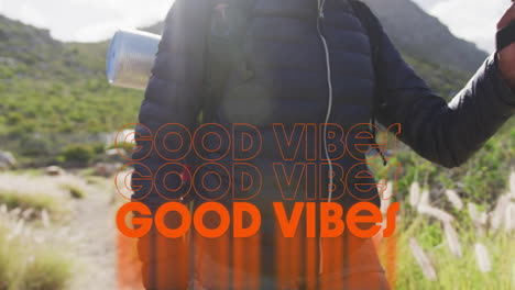 animation of the words good vibes written in orange over person hiking in mountains