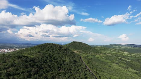 aerial pullback along stunning central american winding mountain road and grassy hillside under a blue sky