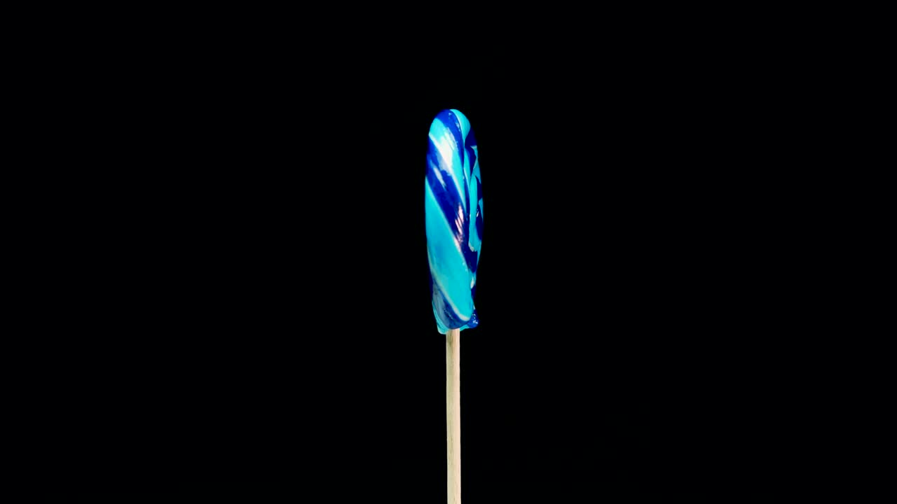 una piruleta de caramelo azul girando sobre un fondo negro. espacio de copia en espiral de caña de caramelos