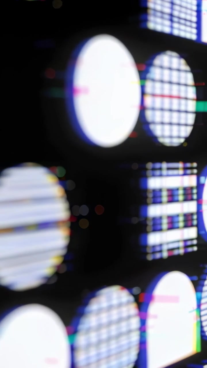 Vertikální video: Telefonem se panorámuje LED panel při laboratorním testování, odhalující kruhové testovací terče a mřížky.