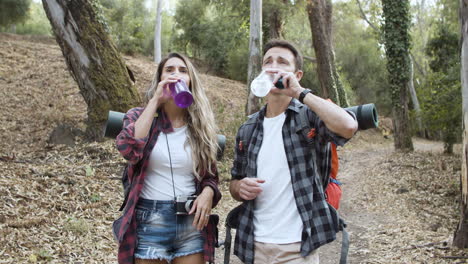 un par de mochileros bebiendo agua fresca y hablando en medio del bosque