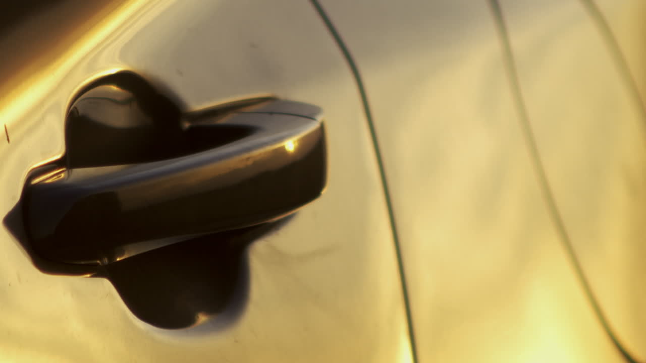 mano agarra el mango del coche y abre la puerta a la luz de la puesta de sol