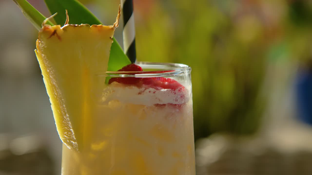 orbita alrededor de la piña cortada en un vaso de pina colada con paja tropical y fondo