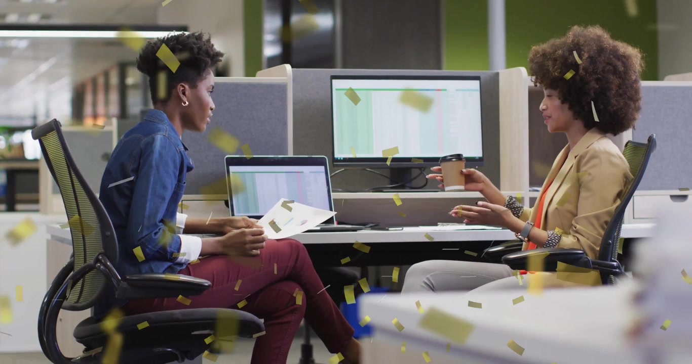 Woman glancing laptop screen starting confetti drifting around two women discussing business charts