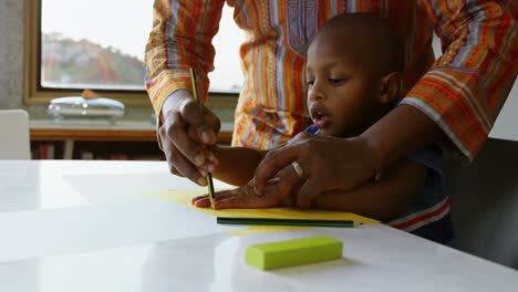 father and son drawing sketch on a paper on table at home 4k