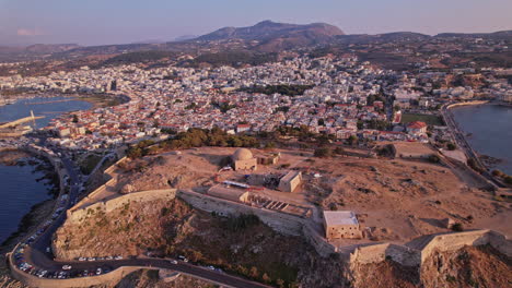 vista aérea de una ciudad costera y una antigua fortificación al atardecer
