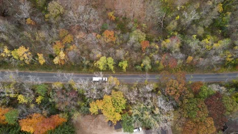 top down view of a white garbage truck driving on the road through the forest in la crosse, wisconsin