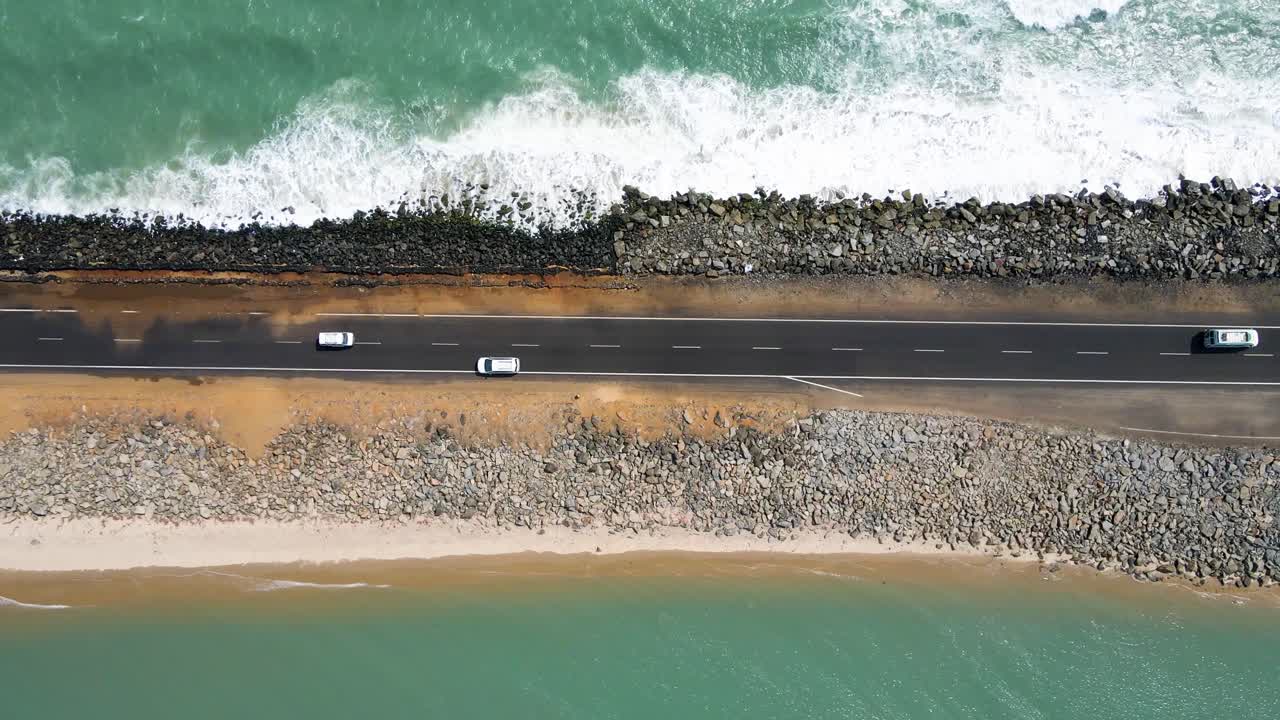 드론으로 찍은 공중 사진, 양쪽 모두 바다 물로 둘러싸인 도로의 위에서 아래로 보이는 모습, 파도가 도로로 는 모습.