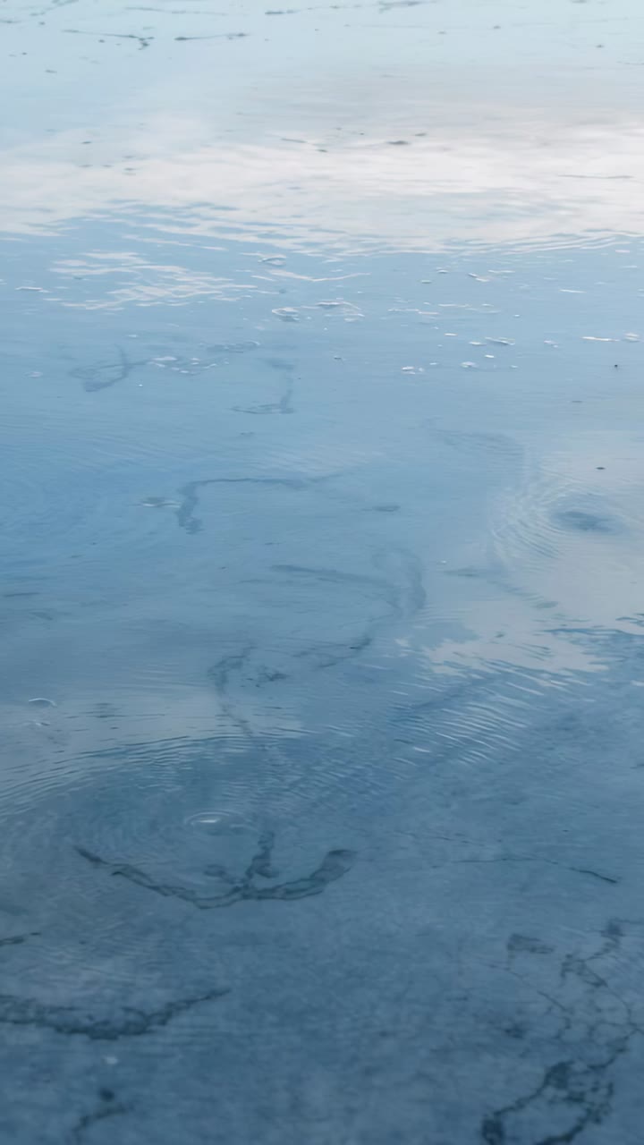 Vertical video: Making water surface ripples after bubble puncture in shallow pond, showing sky
