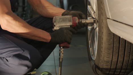 car mechanic replacing a car tire in garage workshop. slow motion. auto service