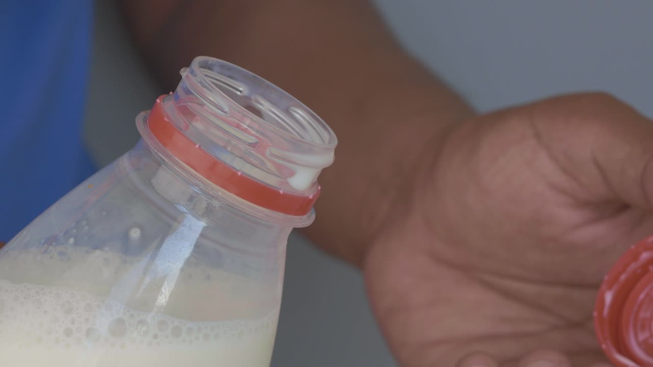 Person opening a milk bottle