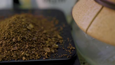 close-up-view-of-finely-ground-coffee-beans-being-scooped-up-on-a-scale-net-to-a-coffee-mug-and-chemix-beaker