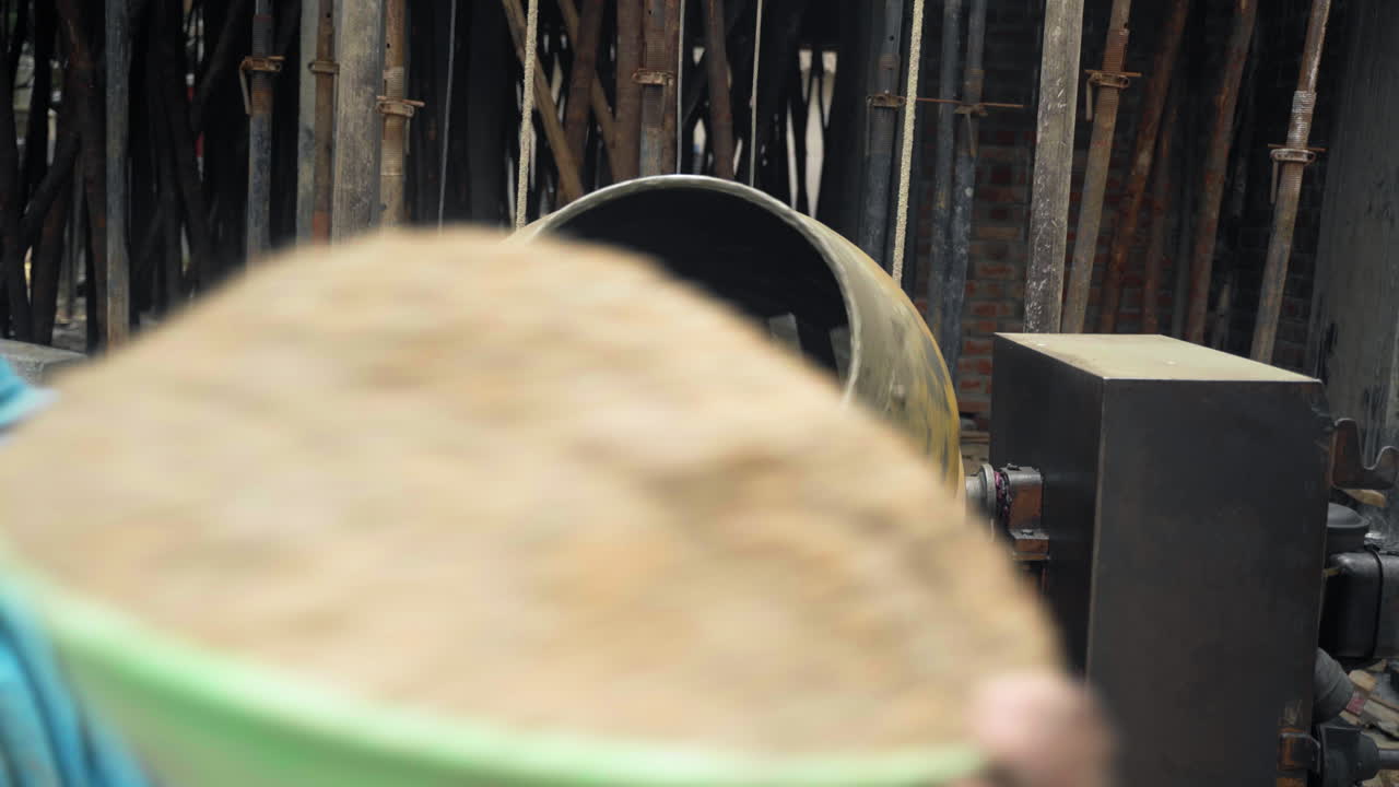 인도에서 건설 노동자 팀이 새로운 집의 지붕을 만들기 위해 콘크리트를 혼합하고 있습니다.