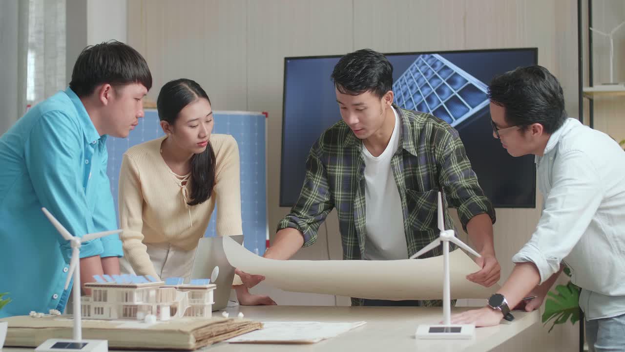 아시아 엔지니어 그룹은 태양 전지 패널 집 모델과 함께 사무실에서 손에 든 블루프린트 작업에 대해 논의합니다.