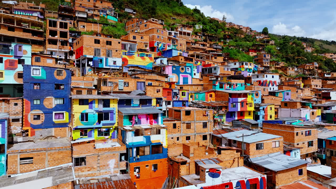 Ripresa aerea con drone di case dipinte su una collina a Medellín, che mostrano colori vivaci, architettura compatta e il dinamico paesaggio residenziale della città
