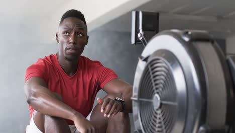 resting after workout, man in gym sitting near rowing machine