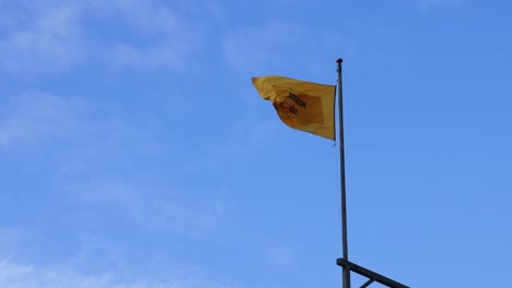 yellow flag waving against blue sky