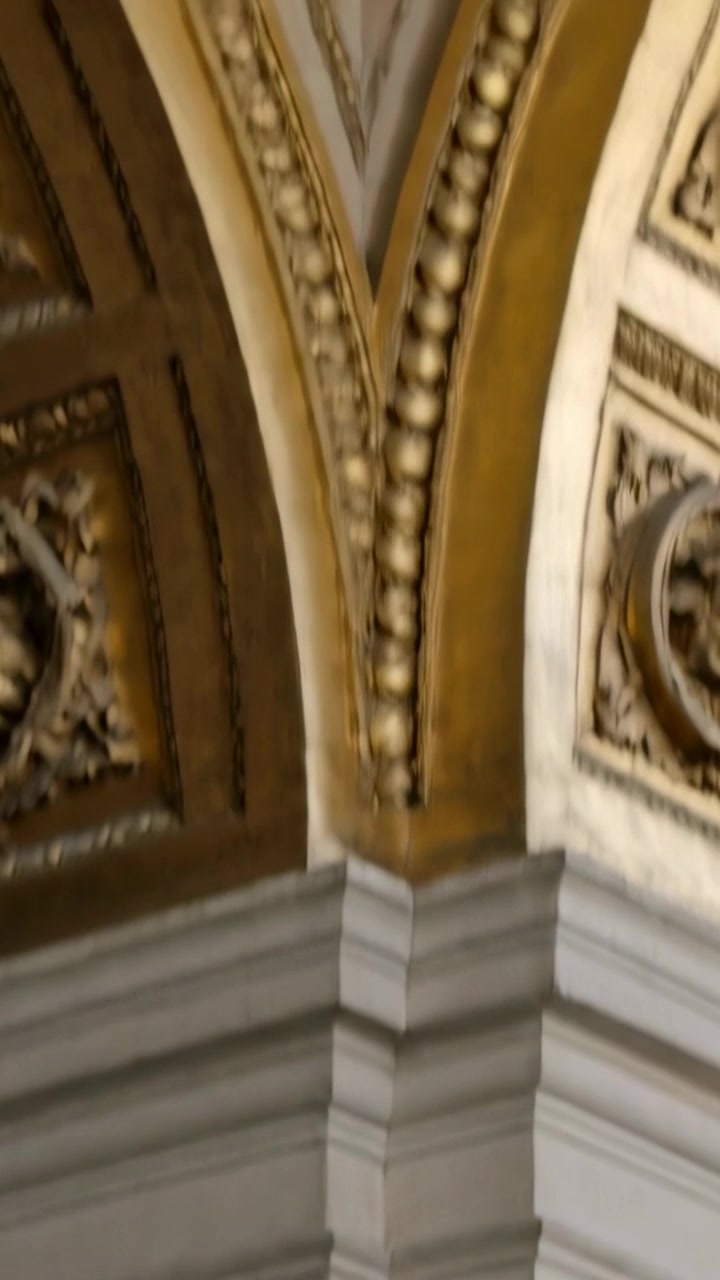 Video verticale: Telecamera che si inclina rivelando un angolo in pietra e un arco dorato in una sala, mostrando il soffitto.